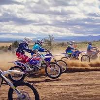 Riders accelerating off the line at the gate drop, throwing dirt behind their rear wheels.