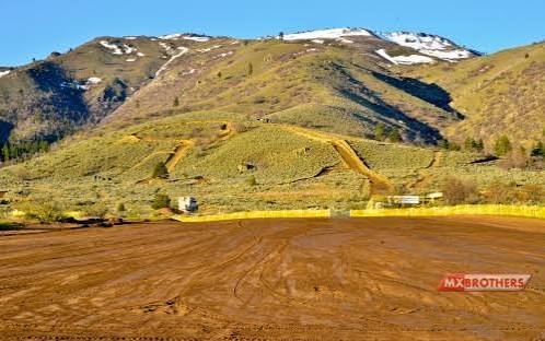 The rebuilt start straight at Honey Lake: groomed hard-pack dirt running toward the hillside track, with snow-capped mountains behind it.
